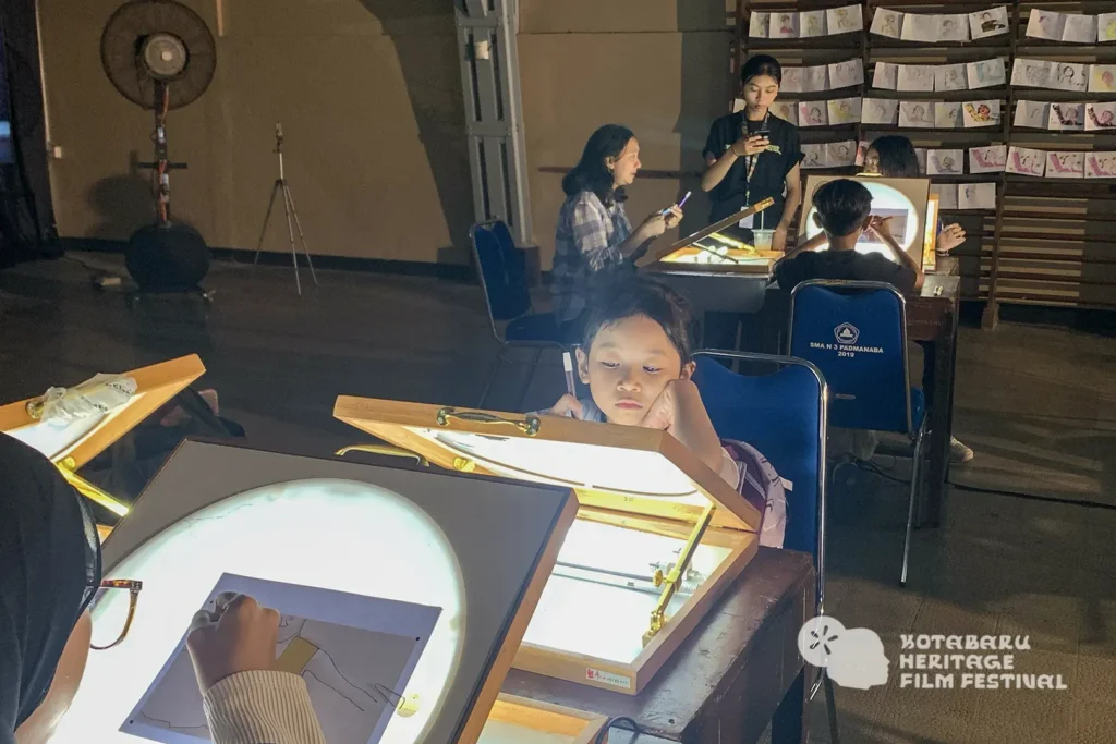 Anak mewarnai frame rotoscoping di meja workshop Tracing The Heritage oleh Rimbun Project, Kotabaru Heritage Film Festival 2025.